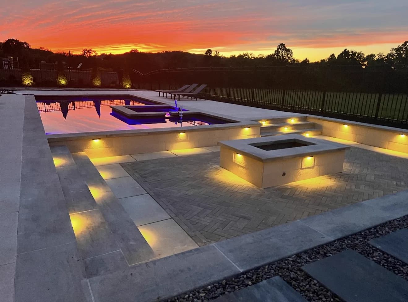 Custom infinity pool with fire bowl and lit interior at sunset, built by Southern Style Hardscapes & Pools in Middle Tennessee