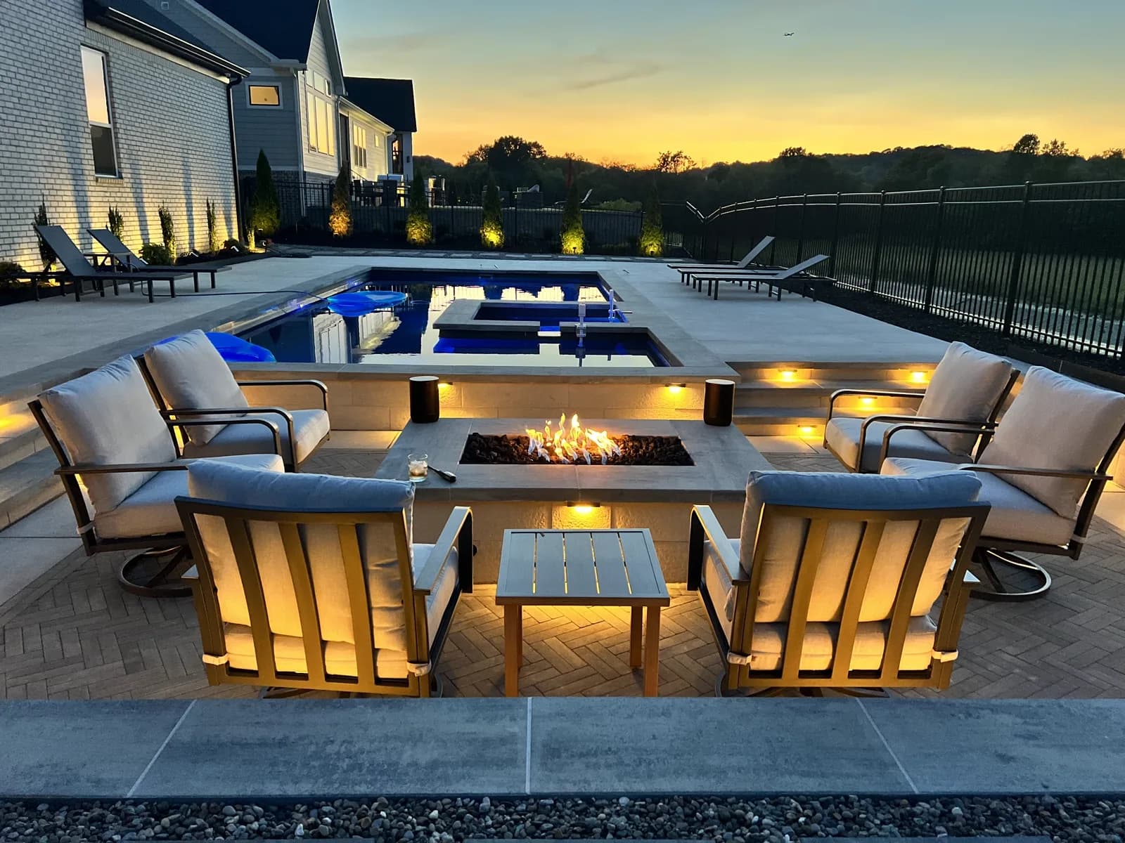 Fire pit seating at dusk with a custom pool glowing behind it in Middle Tennessee