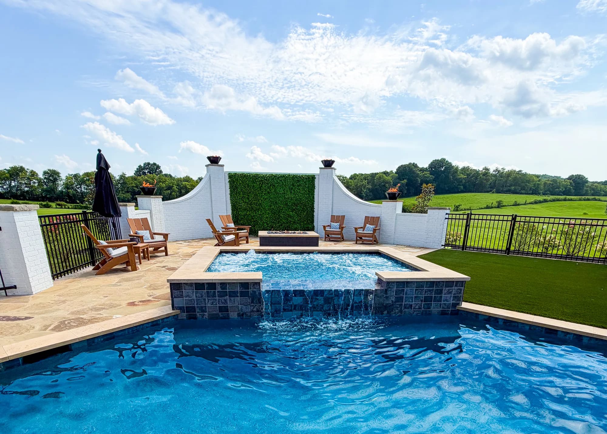 Custom pool framed by raised fire feature walls and stone hardscape
