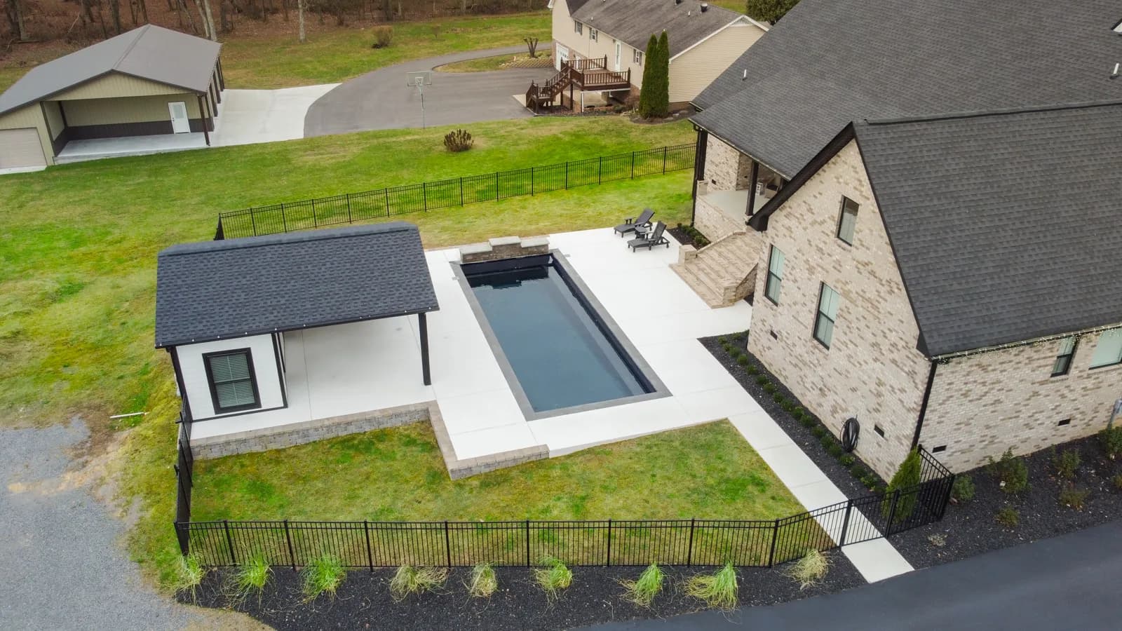 Custom gunite pool with dark interior and travertine deck